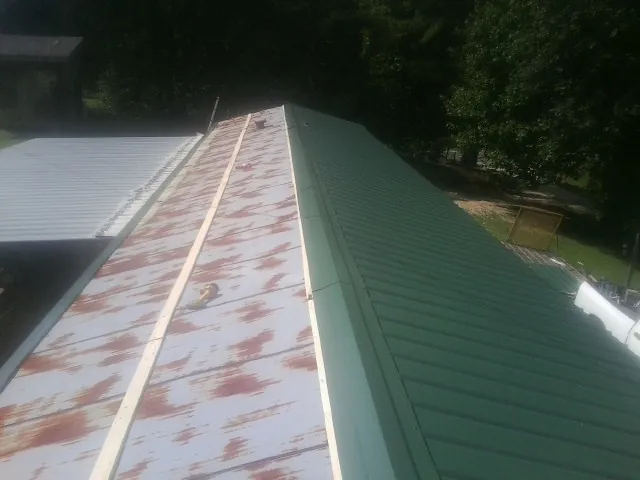 Old rusted panels beside newly installed green metal roofing — Wind Damage Roof Repair by Roofing Brothers in Soap Lake