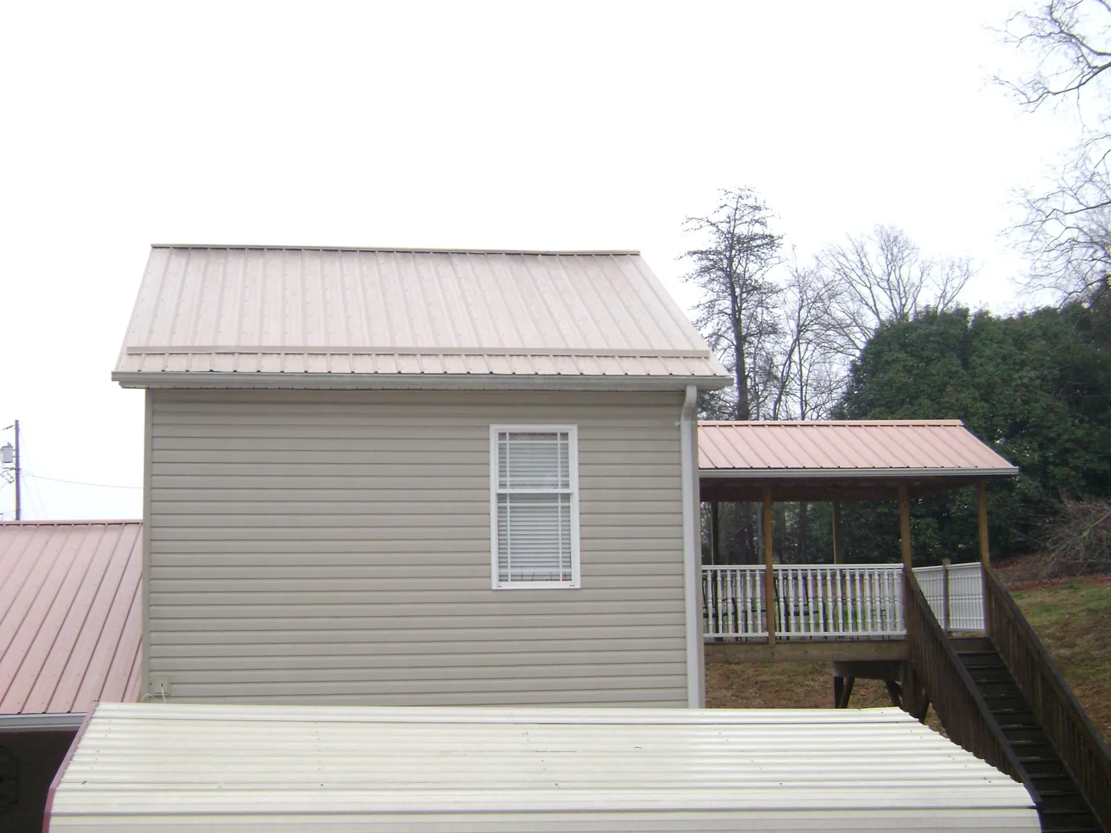 Tan metal roofs on a two story addition and attached porch, from a Roof Replacement job in Soap Lake